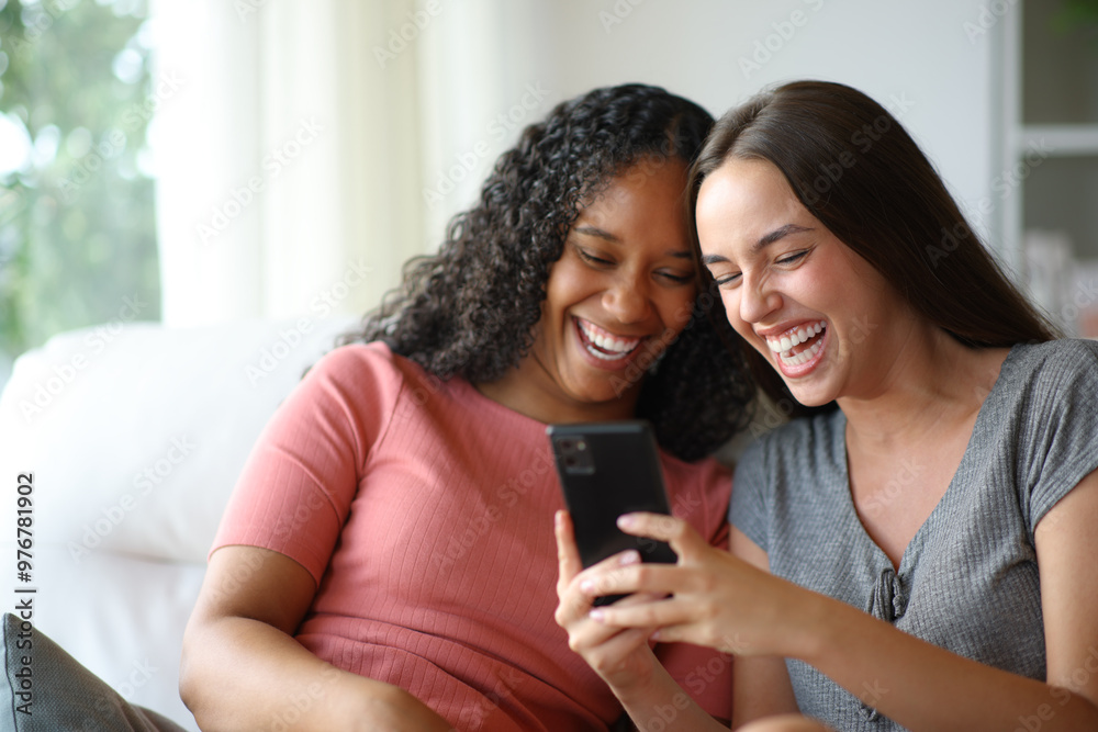 Happy interracial rooomates laughing watching phone content