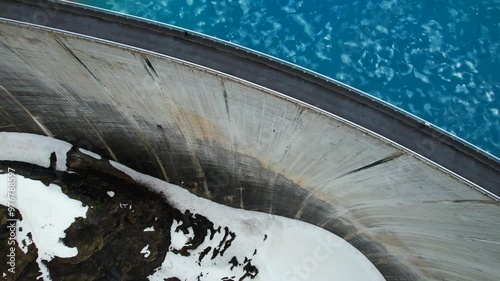 4k Drone Aerial Of Road On Top Of Dam With Vibrant Blue Glacial Water Of Lac de Moiry Dam On lake In Grimentz Switzerland photo