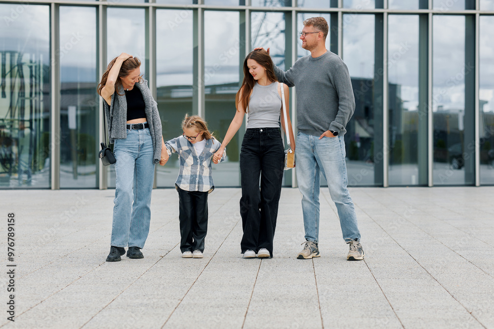 Fototapeta premium A family consisting of a mother, father and two daughters are walking near a business center