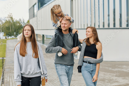 A happy family of mom, dad and two daughters are walking through the city