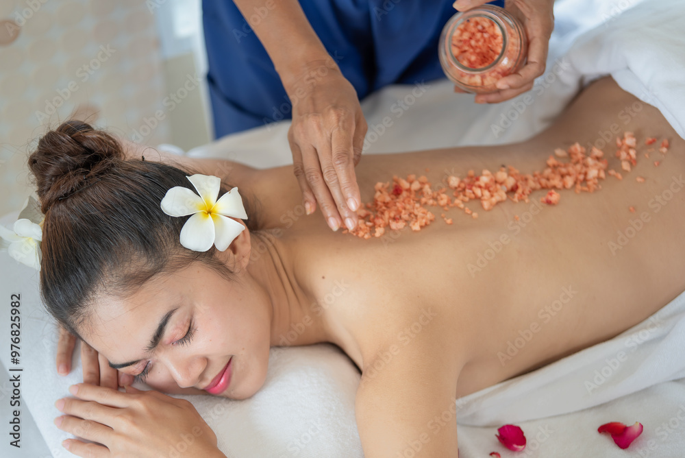 Young Asian woman enjoying in spa salon, Beauty therapist pouring salt scrub on woman back at health spa Young Asian woman enjoying in spa salon, Beauty therapist pouring salt scrub on woman back at health spa
