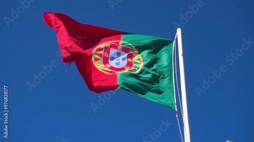 Portugal flag waving in the wind with a clear blue sky backdrop.