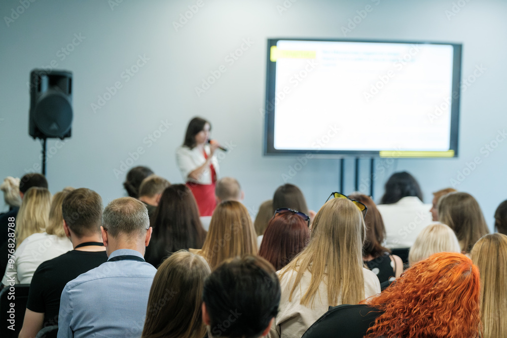 Obraz premium Business professional giving speech at a conference with audience members listening attentively in a seminar room.