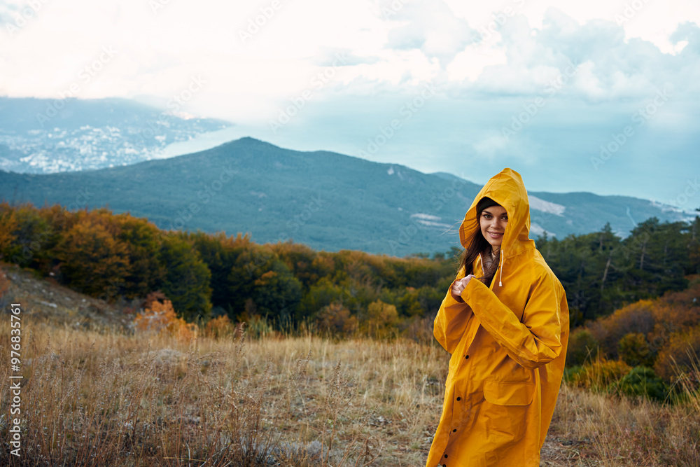 Woman in Yellow Raincoat Enjoying Serene Mountain View on Hilltop During Travel Adventure in Nature Woman in Yellow Raincoat Enjoying Serene Mountain View on Hilltop During Travel Adventure in Nature