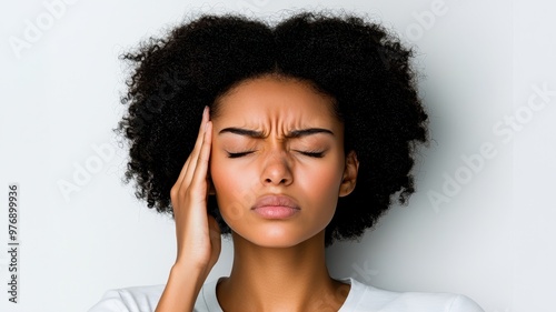 A young woman experiencing discomfort, pressing her temple with a pained expression. Capturing the feeling of stress and tension.