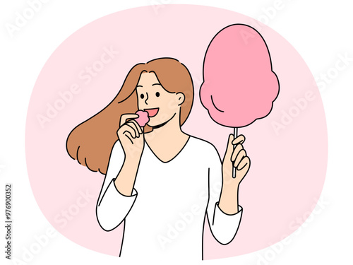 Woman eats cotton candy, enjoying airy sugar dessert while walking in park or at fair. Carefree girl holding cotton candy and experiencing positive emotions from lack of important things to do