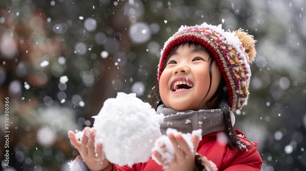 A cute and happy Southeast Asian girl dressing in red winter clothes, holding a snowball on a snowy background with copy space for text. A cute and happy Southeast Asian girl dressing in red winter clothes, holding a snowball on a snowy background with copy space for text.