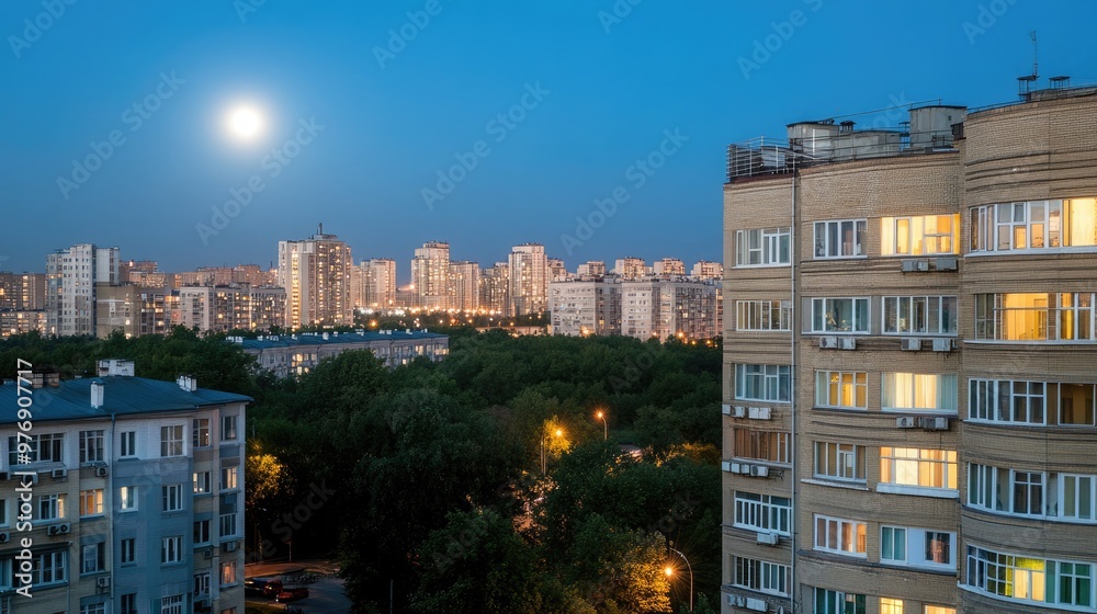 The full moon casts a soft glow over an apartment building, showcasing large windows that reveal the beauty of a modern city illuminated at night The full moon casts a soft glow over an apartment building, showcasing large windows that reveal the beauty of a modern city illuminated at night