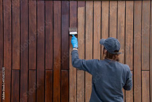 Handy woman improving house hardwood cladding with wood stain application. Do it yourself concept.