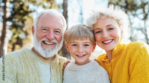 Three family members smile brightly while sharing a warm embrace in a beautiful outdoor location filled with trees