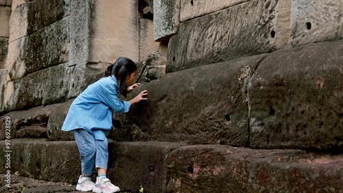 An Asian woman explores Phnom Wan Stone Temple using binoculars to admire its stunning architecture.
