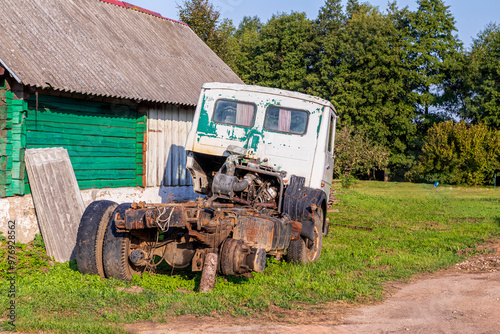 Old abandoned broken big car with flat tires and missing wheel. in the parking lot. Vehicle for recycling and disposal. Dusty and rusty car body.