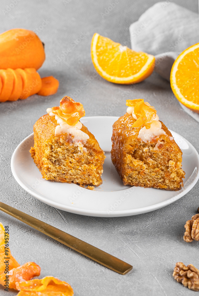 Pieces of delicious carrot cake with nuts, orange and carrot chips on a gray background. Home baking concept. Pieces of delicious carrot cake with nuts, orange and carrot chips on a gray background. Home baking concept.