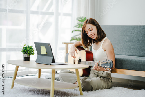 Smiling young woman plays guitar relaxing at home on her vacation. happy young woman Relax on the weekend