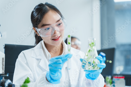 Two Asian women in a lab work on food research, using a microscope, petri dish, and test tubes filled with chemical solutions. They study vegetables, pork, and plants for GMO traits and nutrition.