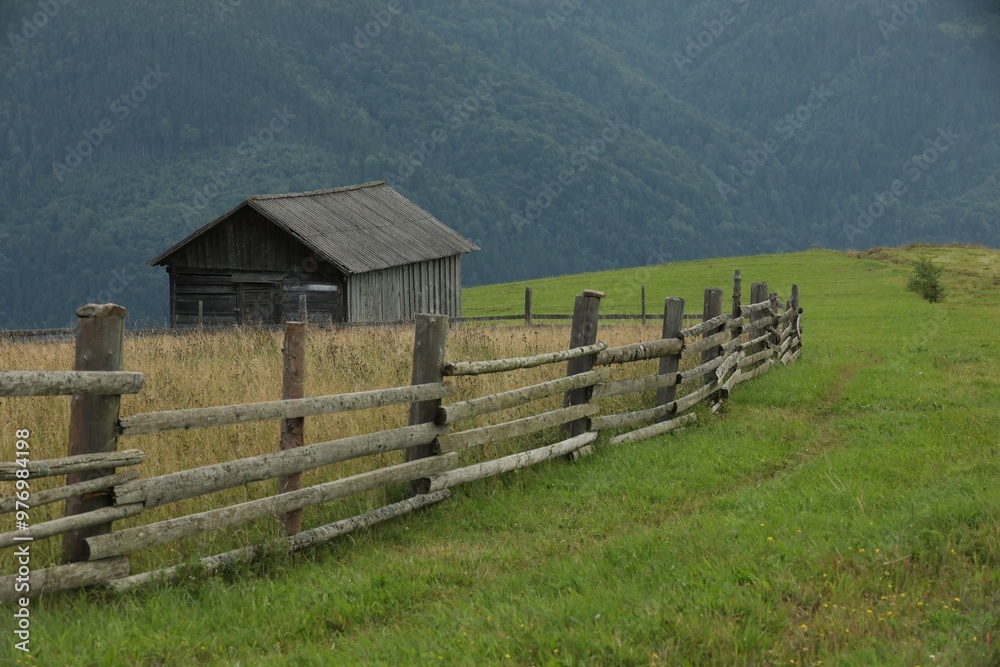 Beautiful view of building and wooden fence in mountains under sky Beautiful view of building and wooden fence in mountains under sky