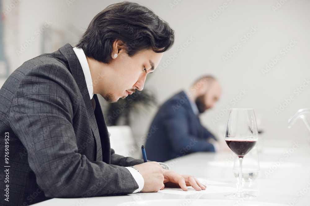 Focused Sommelier Assessing Wine by Tasting during contest. Wine Experts Competition. Focused Sommelier Assessing Wine by Tasting during contest. Wine Experts Competition.