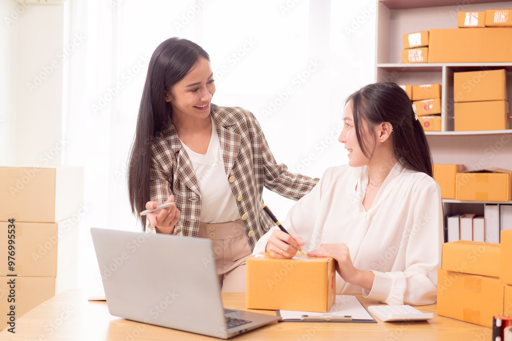 Two Asian SME business owners deliver goods Two women online store owners show happy faces. They are checking orders from customers. They deliver goods through the shipping company. Two Asian SME business owners deliver goods Two women online store owners show happy faces. They are checking orders from customers. They deliver goods through the shipping company.