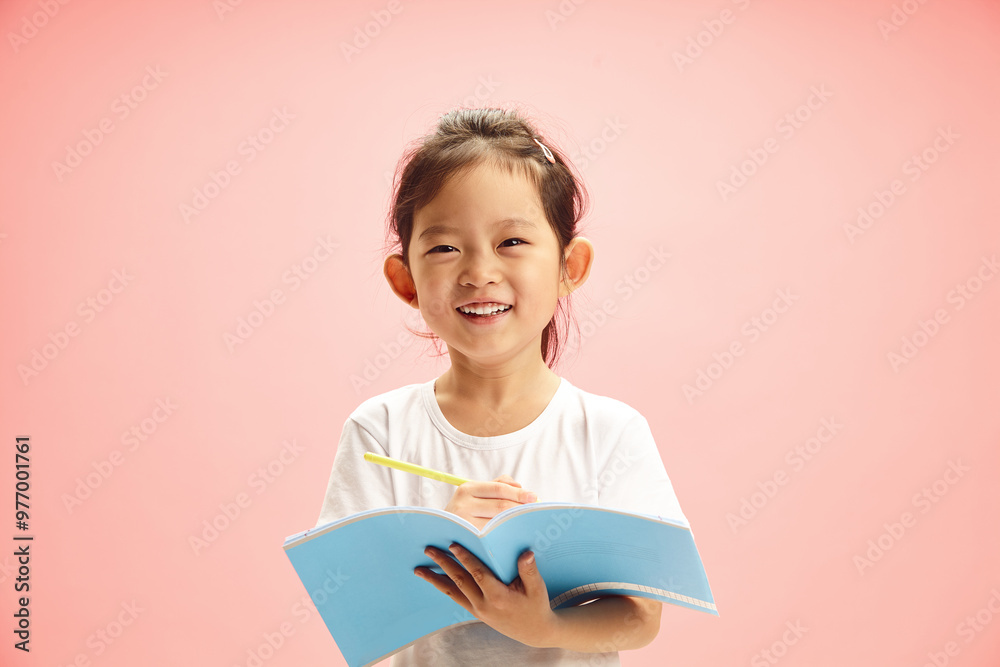 Cheerful First Grader Chinese Girl Smiling while Holding Exercise Book and Pen Standing on Pink Isolated Cheerful First Grader Chinese Girl Smiling while Holding Exercise Book and Pen Standing on Pink Isolated