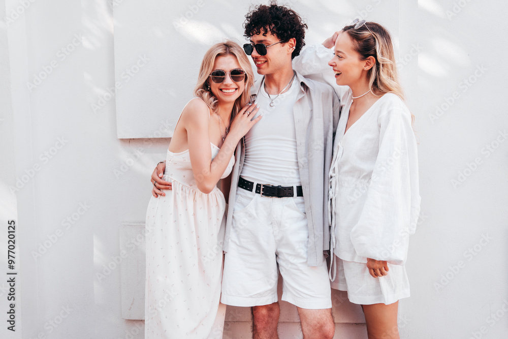 Young three stylish friends posing in the street. Fashion man and two cute female dressed in casual summer clothes. Smiling models having fun. Cheerful women and guy outdoors, in sunny day, sunglasses Young three stylish friends posing in the street. Fashion man and two cute female dressed in casual summer clothes. Smiling models having fun. Cheerful women and guy outdoors, in sunny day, sunglasses