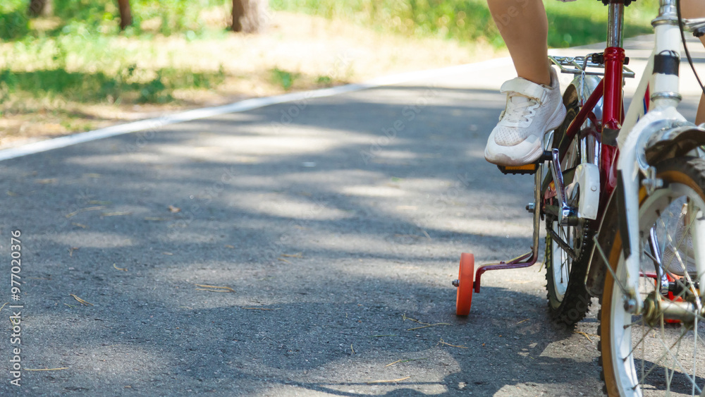 Obraz premium Child bike ride in nature. Child rides bicycle, close-up. Child legs spin pedals. Kid dream of riding bike. Sports lifestyle. Happy family in park.