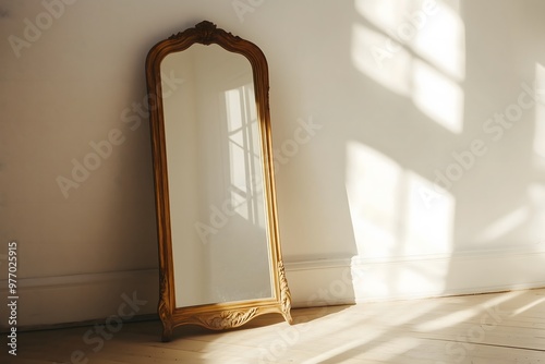 An antique mirror standing on the floor leaning against a white wall
