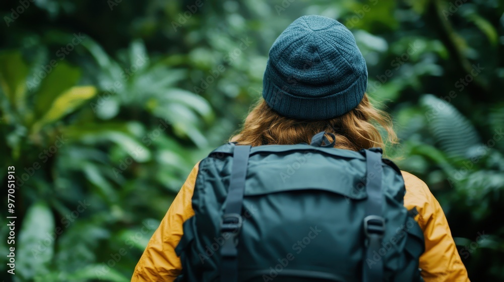Back view of an explorer wearing a beanie and a large backpack, navigating through a lush green forest, symbolizing exploration and tranquility. Back view of an explorer wearing a beanie and a large backpack, navigating through a lush green forest, symbolizing exploration and tranquility.