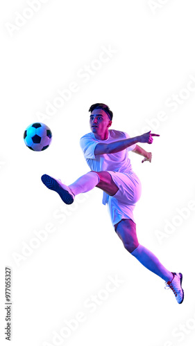 Focused football player, in vibrant neon light during training session, works on controlling ball in air, demonstrating athleticism. Concept of championship, sport events, final game. Ad