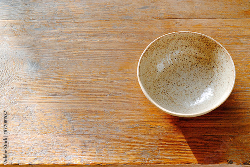 a weathered wooden table with a single, imperfect ceramic bowl, showcasing natural textures and muted colors