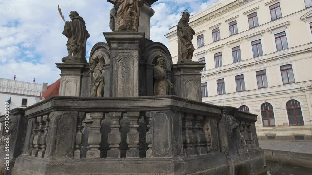 Historic fountain with stone statues in Svornosti Square, Český Krumlov under a bright sky Historic fountain with stone statues in Svornosti Square, Český Krumlov under a bright sky