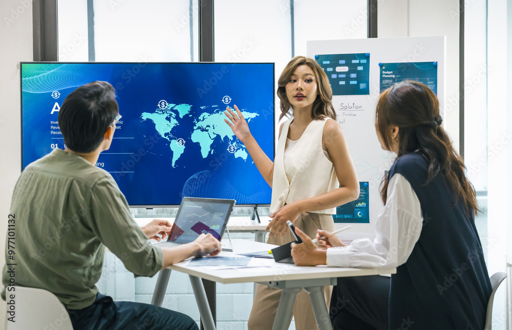 Obraz premium asian leader presenting a financial data and strategies in a modern office with charts and graphs displayed on a large screen
