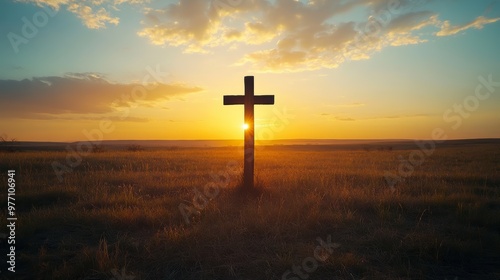 A silhouetted cross stands in a vast field during sunset, with warm hues illuminating the sky and casting a serene atmosphere