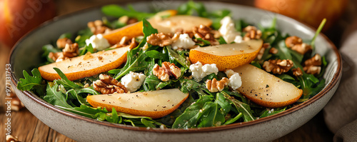 Fresh salad with arugula, pear slices, walnuts, and goat cheese for a healthy and flavorful meal option. photo