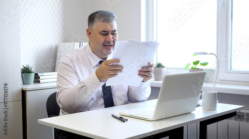 Man in Office Upset While Reviewing Documents at Desk