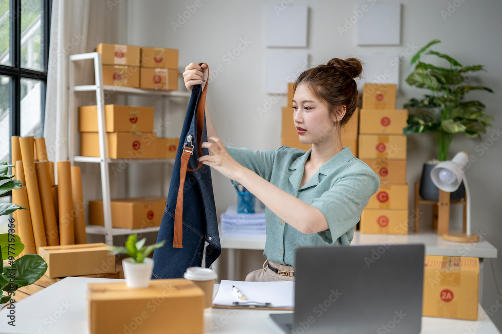 A woman is sitting at a desk with a laptop and a blue apron A woman is sitting at a desk with a laptop and a blue apron