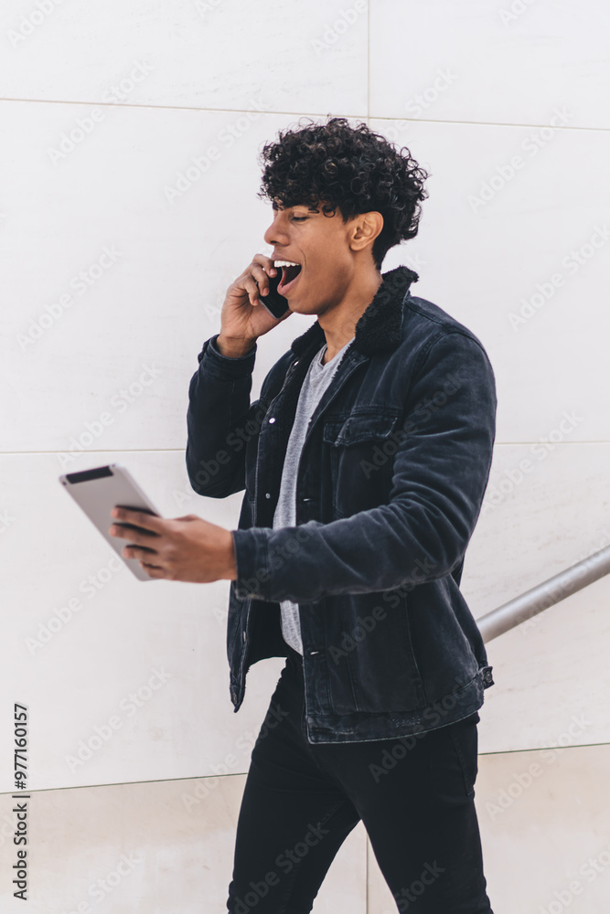 Shocked Latino man checking received email with account balance while walking at urban setting and making smartphone call for discussing information, hipster guy amazed from touch pad notification Shocked Latino man checking received email with account balance while walking at urban setting and making smartphone call for discussing information, hipster guy amazed from touch pad notification