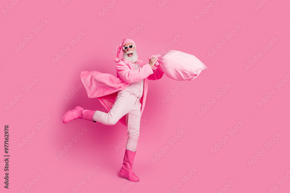 Full size photo of overjoyed man hold new year gift bag empty space wear boots bathrobe isolated on pink color background Full size photo of overjoyed man hold new year gift bag empty space wear boots bathrobe isolated on pink color background