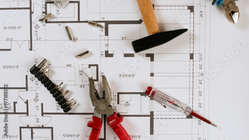 The tools are lying on a paper drawing of the house.