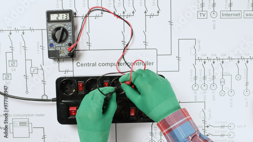 An electrician takes measurements in an extension cord outlet using a voltmeter. A black electrical extension cord on a house electrical plan.