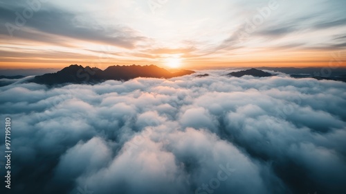 This image shows a breathtaking view of cloud-covered mountains as seen from above during sunrise, with the vibrant colors of the sky and clouds creating a splendid landscape scene.