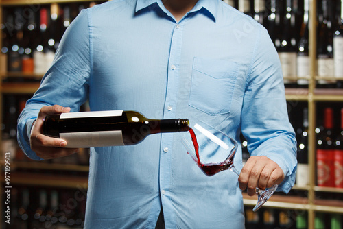 Close-Up of Sommelier Pouring Red Wine Into Glass in Wine Cellar photo