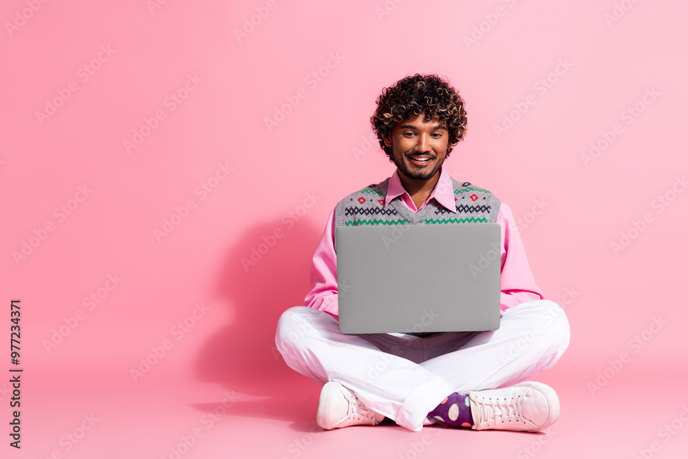 Full body portrait of nice young man use laptop empty space wear xmas new year vest isolated on pink color background Full body portrait of nice young man use laptop empty space wear xmas new year vest isolated on pink color background