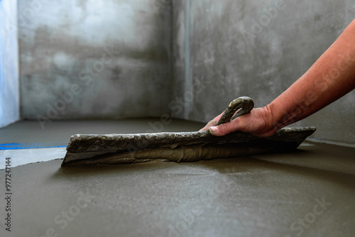 Applying construction glue layer on insulated floor for covering fiberglass reinforcing mesh. photo