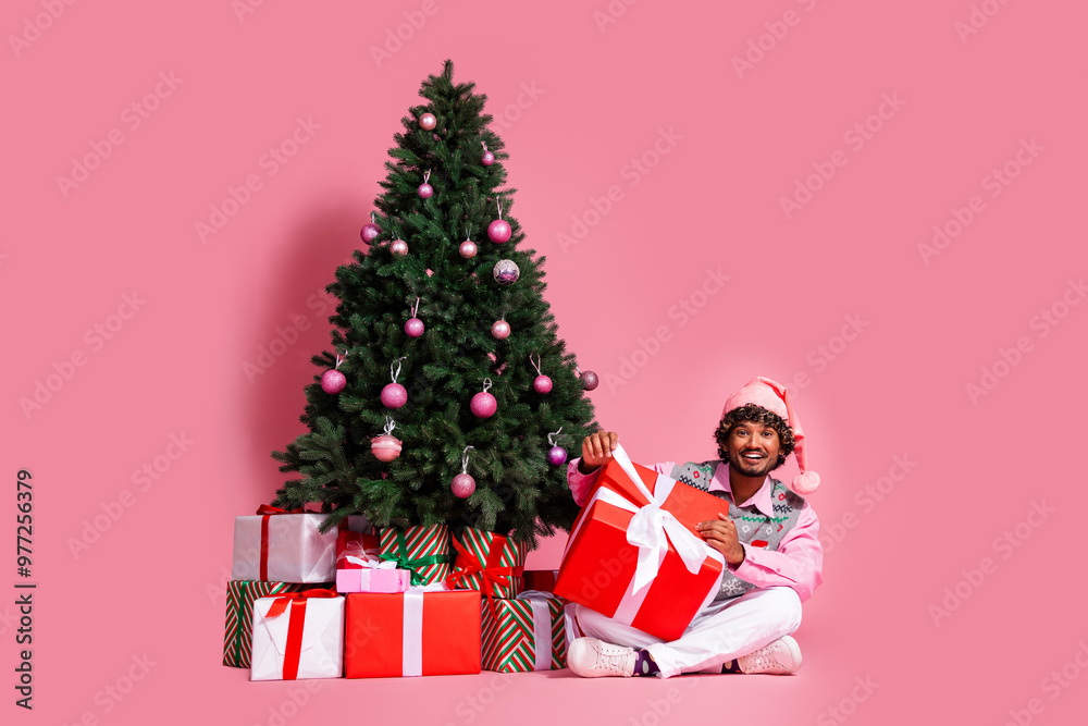 Full length photo of funky cool guy dressed ornament vest santa headwear packing gifts enjoying x-mas day emtpy space isolated pink color background