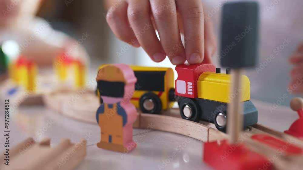 Children play with a toy train in kindergarten. Child childhood fun concept. Train with toy is traveling along lifestyle railway. Children play with toys and trains on the railway in kindergarten.