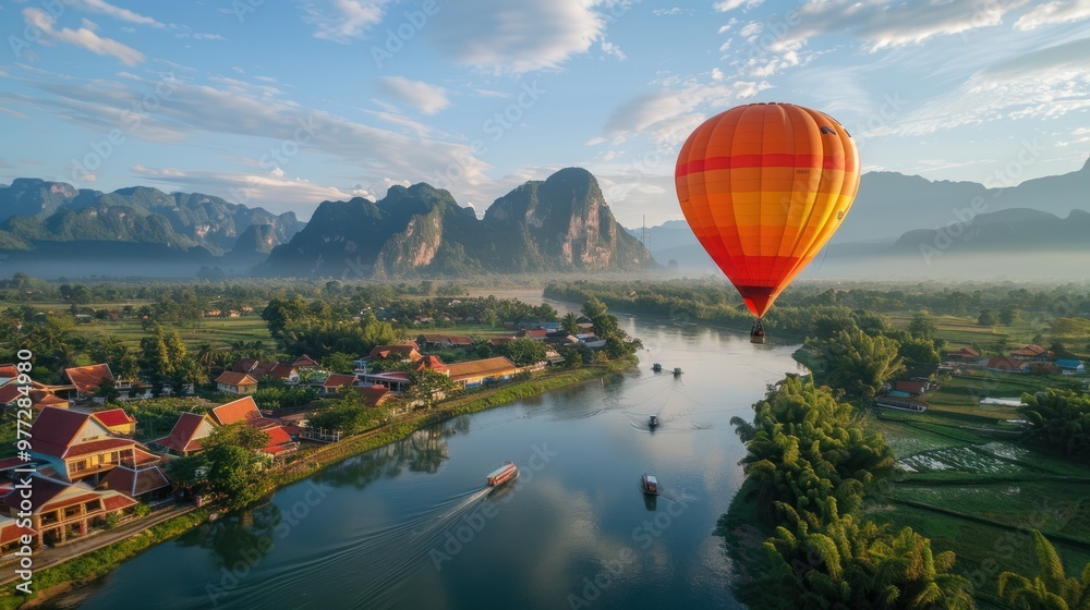 Fototapeta premium A hot air balloon is flying over a town with mountains in the background