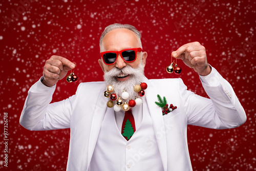 Photo of cheerful retired old positive man hold hands christmas trree balls beard smile isolated on red color background photo