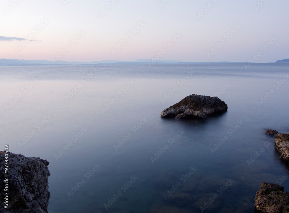 A seaview towards mountains in the distance with rocks in the water. A seaview towards mountains in the distance with rocks in the water.