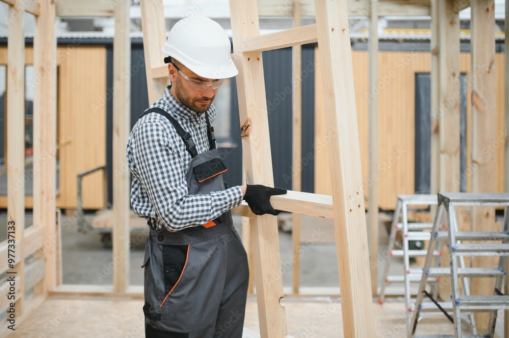 Worker carpenter assembling a modular house Worker carpenter assembling a modular house