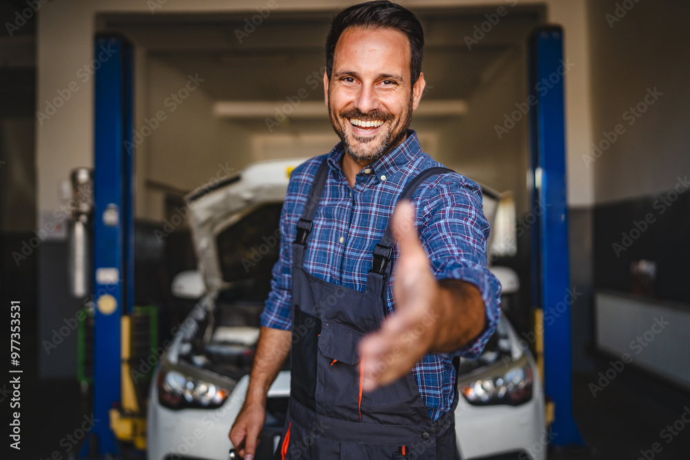 Friendly mechanic reaching out with a smile in auto repair shop Friendly mechanic reaching out with a smile in auto repair shop